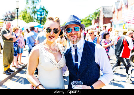 Couple wearing sunglasses smart smartly dressed posing smiling for camera on street UK England GB Stock Photo