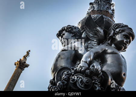 View of Nelson's column and cherubic detail from a lamp post in Trafalgar Square, London, UK. Stock Photo