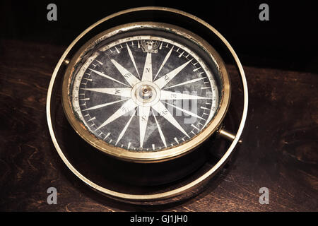 Vintage compass with old Russian coat of arms lays on dark wooden table, close up photo with selective focus and warm retro tona Stock Photo