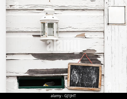 White rural wooden wall with black chalkboard, candle lamp and mailbox hole, background photo texture Stock Photo