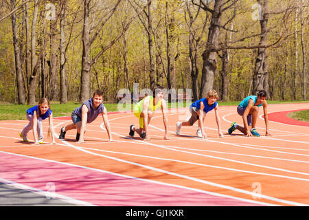 Five teens standing on starting position at track Stock Photo