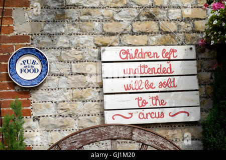 joking passive sign stating children left unattended will be sold to the circus at a traditional uk country pub