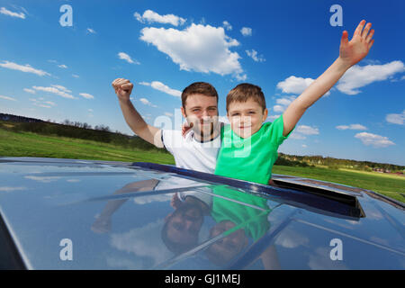 Father and son enjoying freedom on sunroof of car Stock Photo