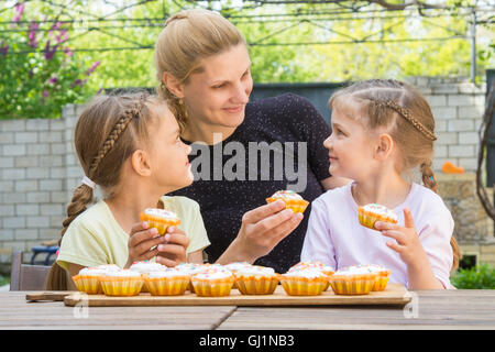 Mother and two daughters sitting at the table with Easter cupcakes in his hands Stock Photo