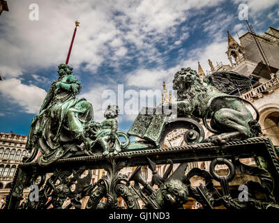 Bronze statues on gates of the loggetta of San Marco campanile, with Basilica di San Marco in the background. Venice, Italy. Stock Photo