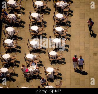 Aerial view of neatly arranged tables and chairs with crisp white tablecloths in St Mark’s Square, Venice, on a hot sunny day. Italy Stock Photo