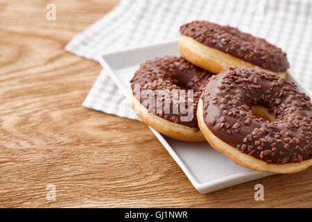 Glazed chocolate donut on wooden background Stock Photo