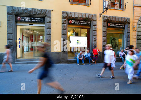 Pedestrians pass a branch of the Monte dei Paschi di Siena bank on Via Banchi di Sopra in Siena, Italy. Stock Photo