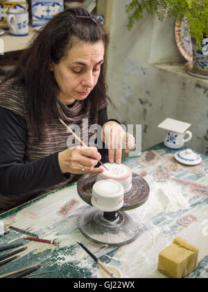 A final signature on a pottery cup. A woman worker paints a signature on a piece of pottery at the Ceramic Vieira factory Stock Photo