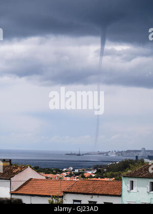 Waterspout over Ponta Delgada. A tornadic waterspout appears from the dark storm clouds in the ocean just beyond the city centre Stock Photo