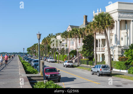 People walk and jog across from historic antebellum mansions on Battery Row, in Charleston, South Carolina. Stock Photo
