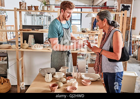 Potter in workshop showing customer pottery Stock Photo