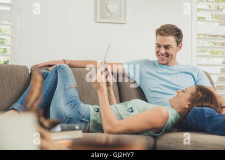Couple relaxing on sofa using digital tablet smiling Stock Photo