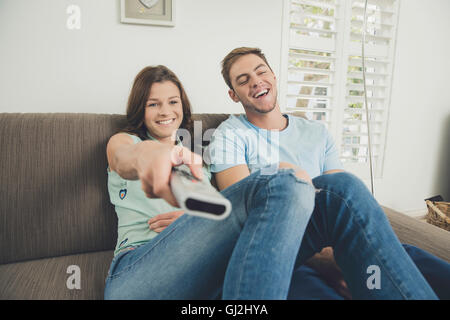 Couple on sofa using remote control smiling Stock Photo