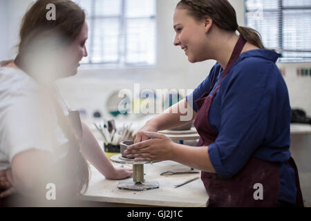 Female potters shaping clay pot in workshop Stock Photo