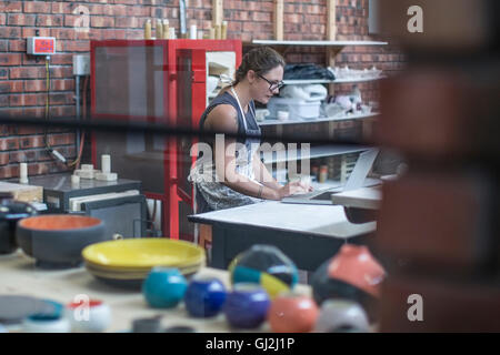 Female potter checking online orders in workshop Stock Photo