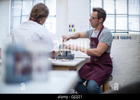 Male potter shaping clay pot on wheel in workshop Stock Photo
