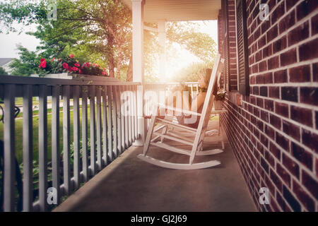 Girls on porch in rocking chair using digital tablet Stock Photo