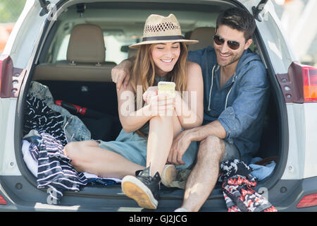 Couple in car boot looking at smartphone Stock Photo