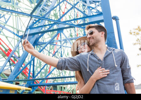 Couple at fairground using smartphone to take selfie, Coney island, Brooklyn, New York, USA Stock Photo