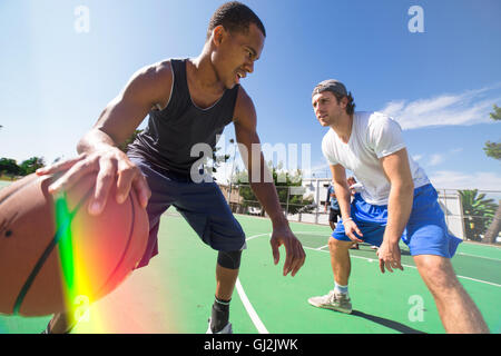 Two male friends playing basketball on outdoor court Stock Photo