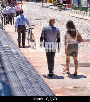 Business people walking along street, mature man pushing bike, rear view Stock Photo