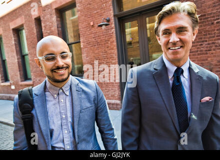 Two businessmen walking together in street, smiling Stock Photo