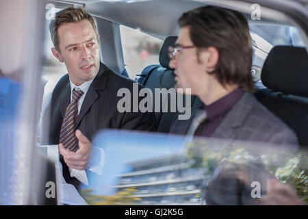 Two businessmen talking in car back seat Stock Photo