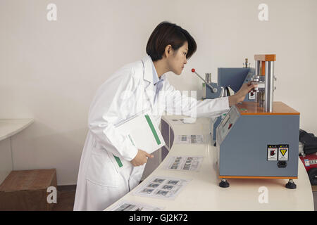 Female technician operating printing machine in printing and packaging factory, China Stock Photo