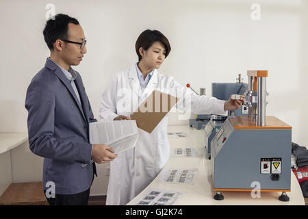 Technician explaining printing machine to manager in printing and packaging factory, China Stock Photo