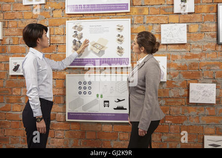 Worker showing framed product to manager on printing and packaging factory wall, China Stock Photo