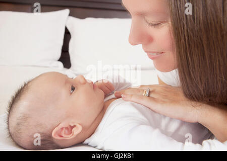 Mother admiring baby boy lying on bed Stock Photo