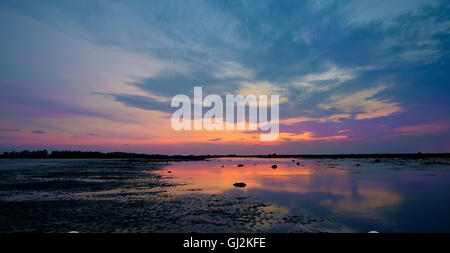 Colourful sunrise and stones in  low tide ocean water Stock Photo