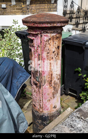 Old, faded and decaying British red post box seen in London, UK. Stock Photo