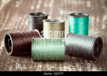 Bobbins with colorful threads on wooden  background Stock Photo