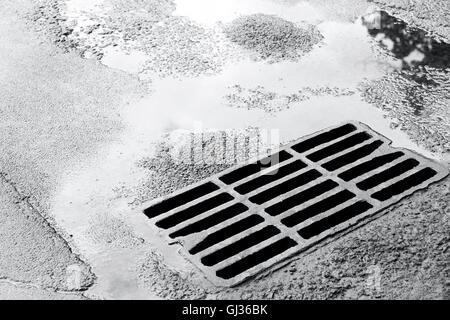 metal sewer grate for drainage system on wet asphalt road Stock Photo