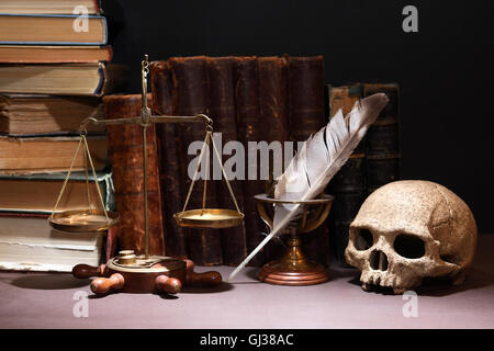 Old brass weight scales near skull and quill on books background Stock Photo