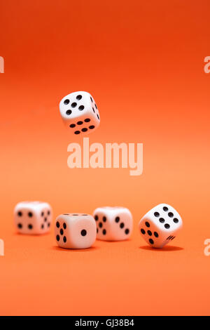 Dice game. One dice cube falling to another dices on red background Stock Photo