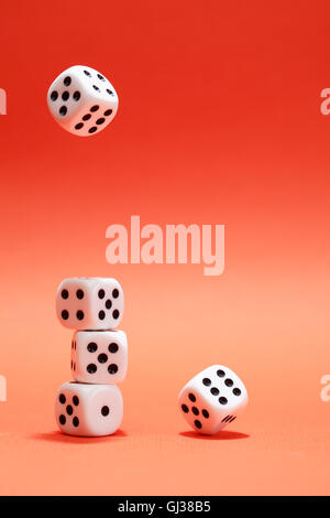 Dice game. One dice cube falling to another dices on red background Stock Photo