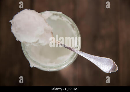 Overhead view of spoonful of cold coconut oil on jar Stock Photo