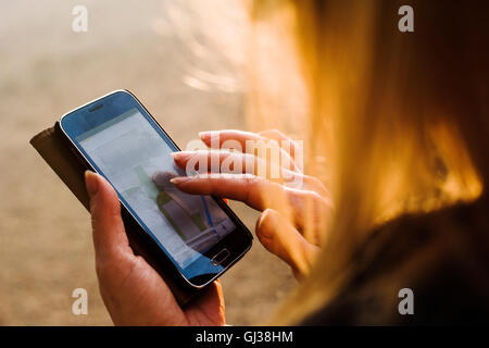 Young woman outdoors, using smartphone, close-up Stock Photo