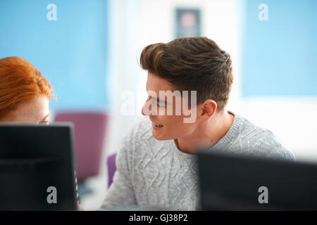 Young male and female college students having discussion at computer desk Stock Photo
