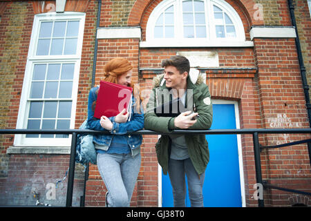 Young college student couple leaning against campus handrail chatting Stock Photo