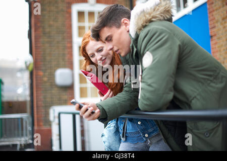 Young male and female college students reading smartphone text on campus Stock Photo
