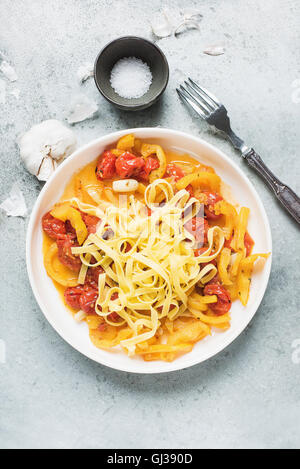 Pasta tagliatelle with cherry tomato sauce and garlic on white plate Stock Photo
