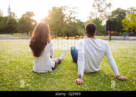 Rear view of young couple sitting on grass Stock Photo