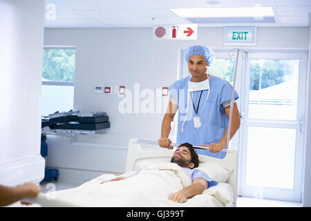 Doctors wearing surgical scrubs pushing patient on hospital bed Stock Photo