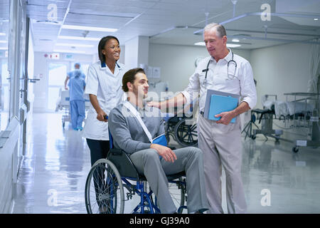 Doctor consulting with man in wheelchair with arm sling Stock Photo