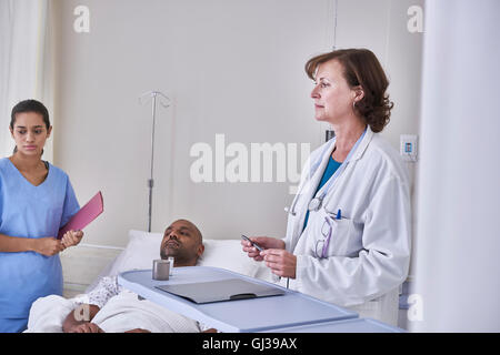 Doctors diagnosing patient lying in hospital bed Stock Photo