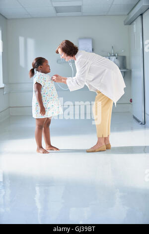 Female doctor using stethoscope on girl in hospital children's ward Stock Photo